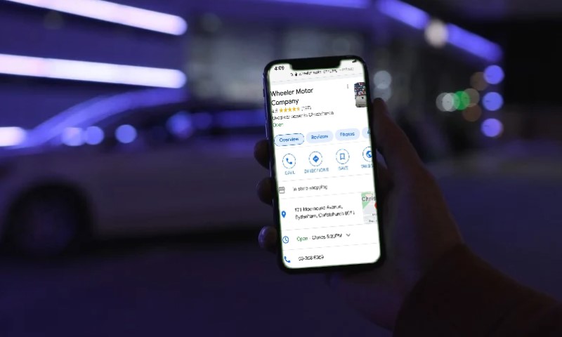 A hand holds a smartphone displaying a map app for "Wheeler Motor Company"