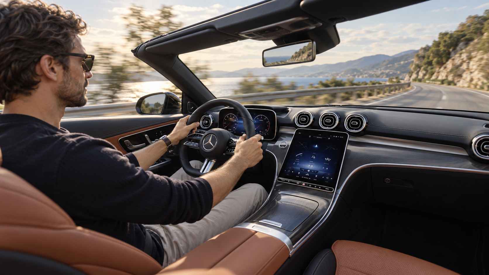 Driver inside a Mercedes C300 Cabriolet on a coastal road.